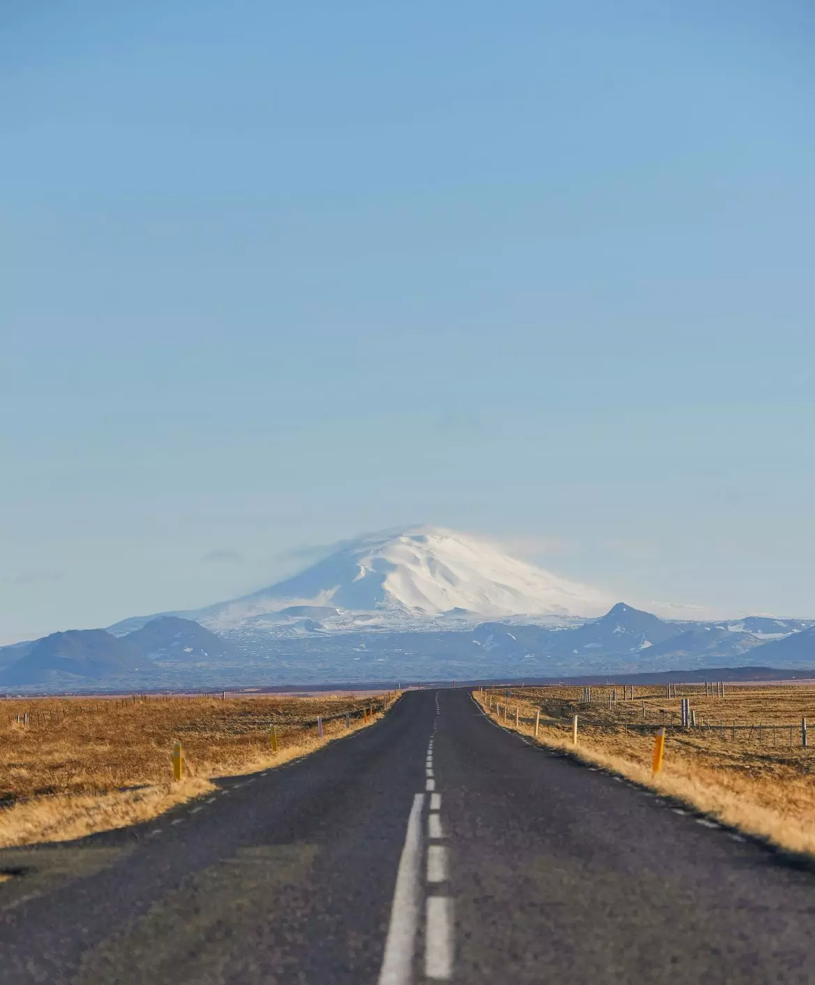 Chemin vers la montagne enneigée – symbole de la thérapie et de la découverte de soi. Route vers une montagne enneigée sous un ciel bleu, symbolisant le chemin de croissance personnelle et de transformation en psychothérapie.